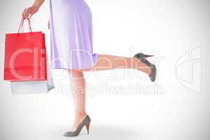 Mid section of woman in dress holding shopping bag