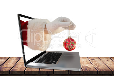 Composite image of santas hand is holding a christmas bulb