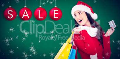 Composite image of festive brunette holding shopping bags and cr