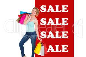 Composite image of smiling blonde woman standing with shopping b