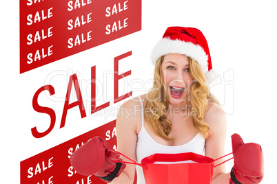 Composite image of shocked blonde opening a shopping bag with bo