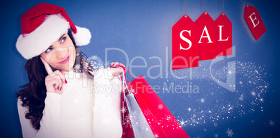 Composite image of festive brunette holding shopping bags and th