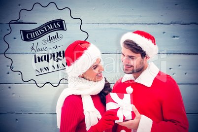 Composite image of festive young couple holding gift