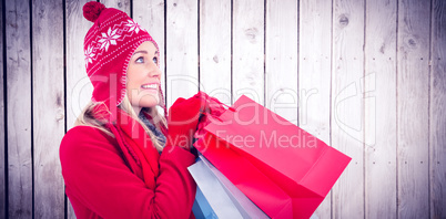 Composite image of blonde in winter clothes holding shopping bag