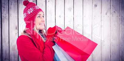 Composite image of blonde in winter clothes holding shopping bag