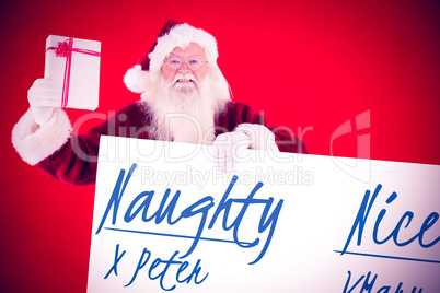 Composite image of santa shows a present while holding sign