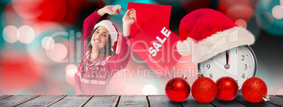 Composite image of pretty brunette showing sale bag and shopping