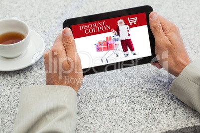 Composite image of businessman holding small tablet at table