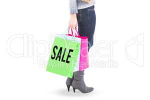 Composite image of blonde in winter clothes holding shopping bag