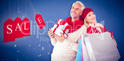 Composite image of happy festive couple with gifts and bags