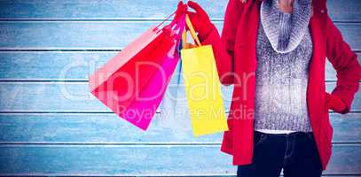 Composite image of blonde in winter clothes holding shopping bag