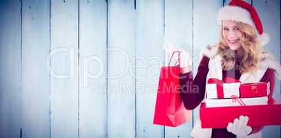 Composite image of festive blonde with shopping bag and gifts