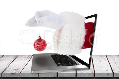 Composite image of santa claus holding red bauble