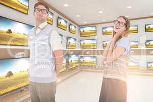 Composite image of geeky hipster couple looking at camera