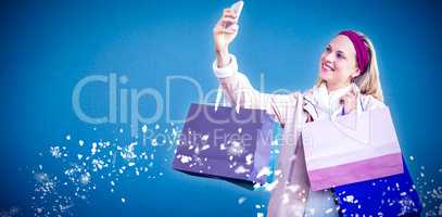 Composite image of smiling woman with shopping bags taking selfi