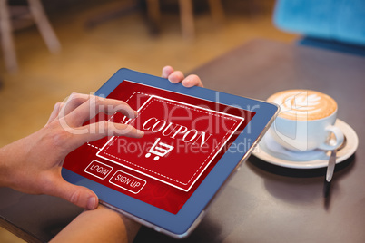 Composite image of hand holding digital tablet by table at home