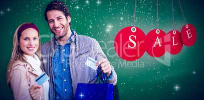 Composite image of smiling couple with shopping bags showing cre