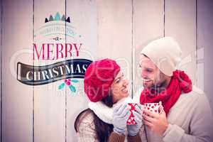 Composite image of winter couple holding mugs