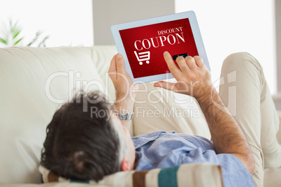 Composite image of man laying on sofa using a tablet pc