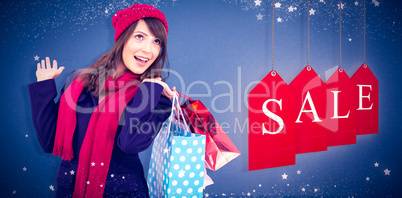 Composite image of happy brunette in winter clothes holding shop