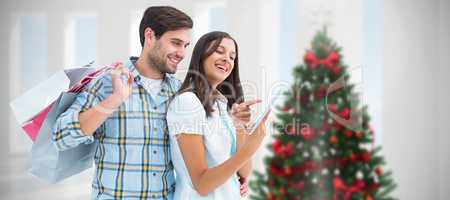 Composite image of happy couple with shopping bags and tablet