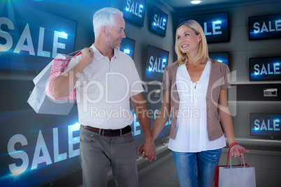 Composite image of happy couple with shopping bags