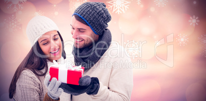 Composite image of winter couple holding gift