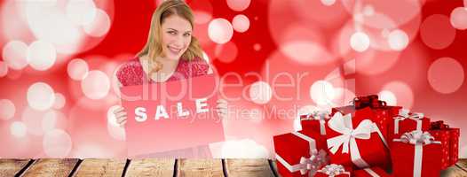 Composite image of smiling blonde showing a red sale poster