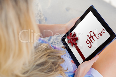 Composite image of woman sitting on beach in deck chair using ta