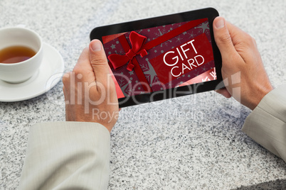 Composite image of businessman holding small tablet at table