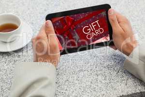 Composite image of businessman holding small tablet at table