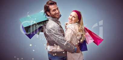 Composite image of smiling couple with shopping bags embracing