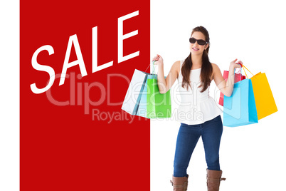 Composite image of cheerful brunette holding shopping bags