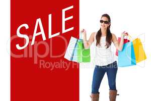 Composite image of cheerful brunette holding shopping bags