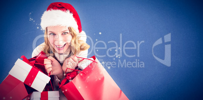 Composite image of girl in winter fashion holding presents and s