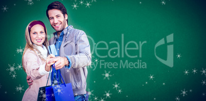 Composite image of smiling couple showing credit card and shoppi