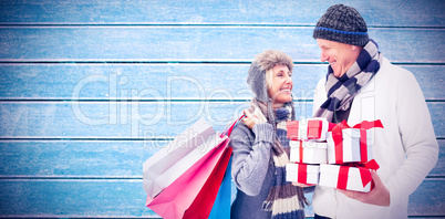 Composite image of festive mature couple holding christmas gifts