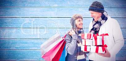 Composite image of festive mature couple holding christmas gifts