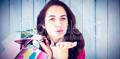 Composite image of woman holding shopping bags and throwing a ki