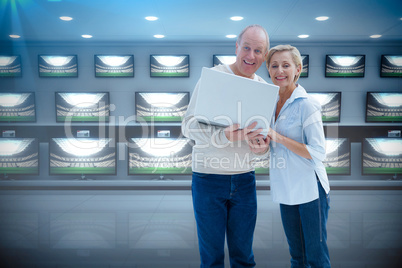 Composite image of mature couple smiling at camera with laptop