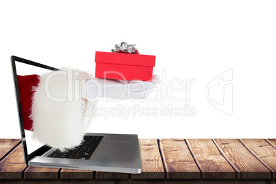 Composite image of hand of santa claus holding a gift