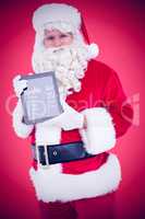 Composite image of happy santa showing digital tablet
