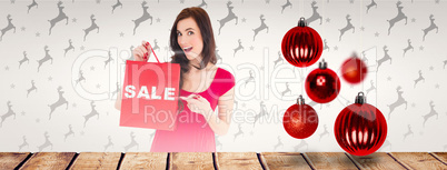 Composite image of stylish brunette in red dress showing sale ba
