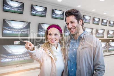 Composite image of smiling couple looking and pointing