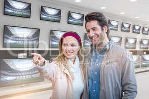 Composite image of smiling couple looking and pointing