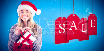 Composite image of festive blonde holding christmas gift and bag