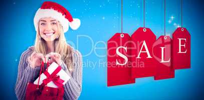 Composite image of festive blonde holding christmas gift and bag