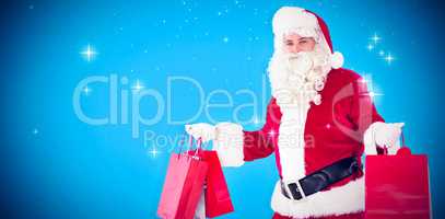 Composite image of smiling santa claus holding shopping bags