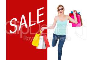 Composite image of happy blonde holding shopping bags