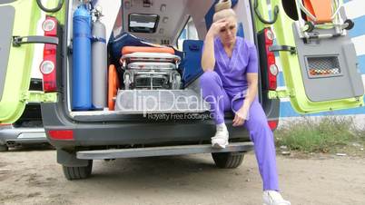 Emergency medical service upset tired paramedic sitting in front of ambulance